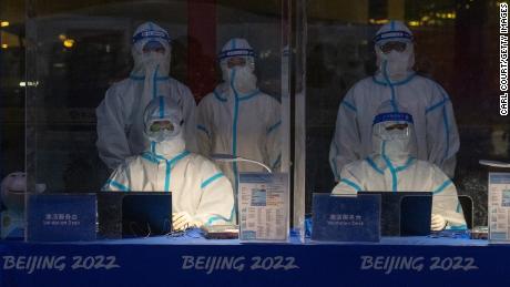 Officials decked in personal protective equipment wait to validate Olympic accreditation for people arriving at Beijing Capital International Airport on January 24.